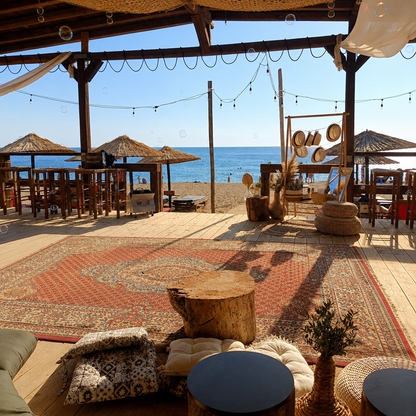 Boho beach wedding decoration at sunset with wooden aisle, floral arches and lanterns in Athens, Greece.