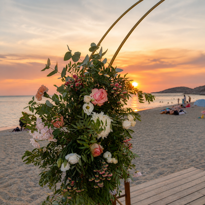 Boho beach wedding decoration at sunset with wooden aisle, floral arches and lanterns in Athens, Greece.